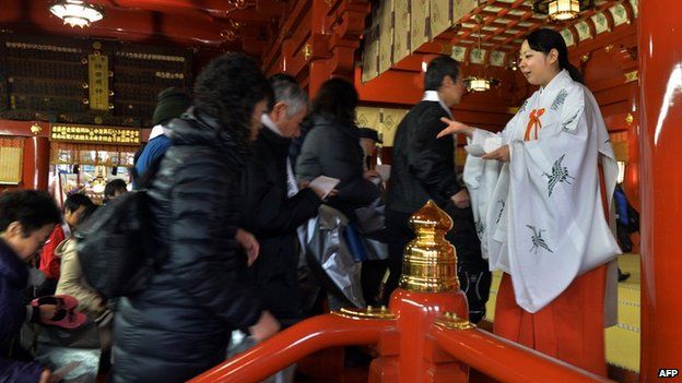 A Japanese Shinto maiden (R) greets worshippers as they enter the Kanda shrine to celebrate the New Year in Tokyo on January 1, 2014