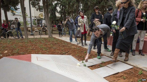 People lay flowers at a memorial to thousands of gay Holocaust victims killed by the Nazi during the Second War at the Gan Meir (Meir Park) during its inauguration on January 10, 2014 in the Mediterranean coastal city of Tel Aviv