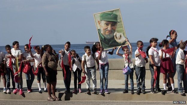 School children stand in Havana while holding a photograph of Cuba's former President Fidel Castro