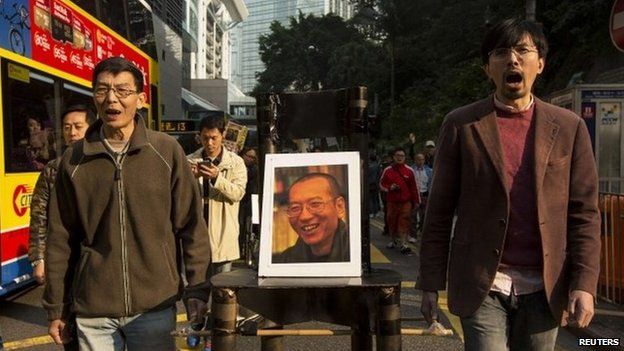Pro-democracy protesters carry a seat with a posters of Chinese Nobel Peace Prize laureate Liu Xiaobo during a protest to urge for the release of jailed Liu and his wife Liu Xia in Hong Kong, 25 December 2013