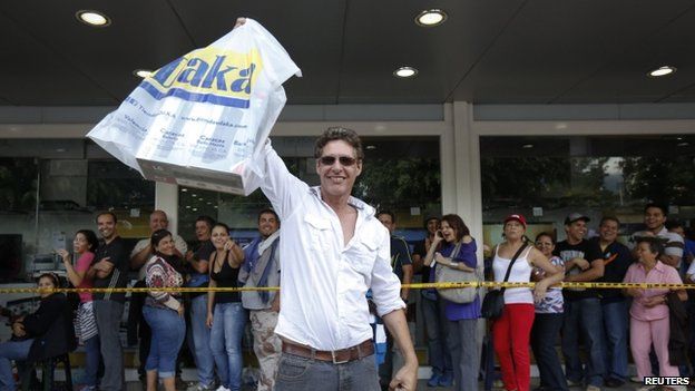 A shopper holds up a bag containing his newly purchased electronics outside a Daka store in Caracas on 9 November, 2013