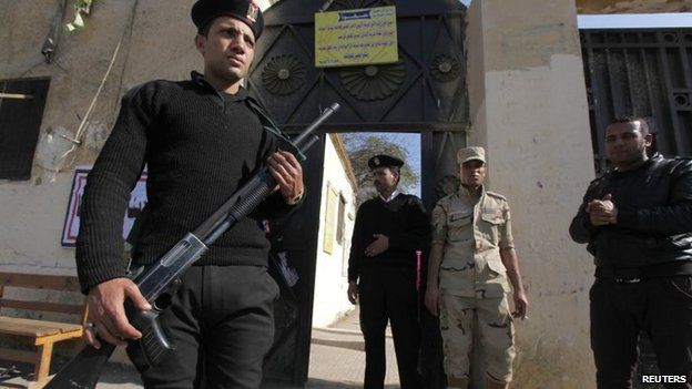 Egyptian police and a soldier stand guard outside a polling station