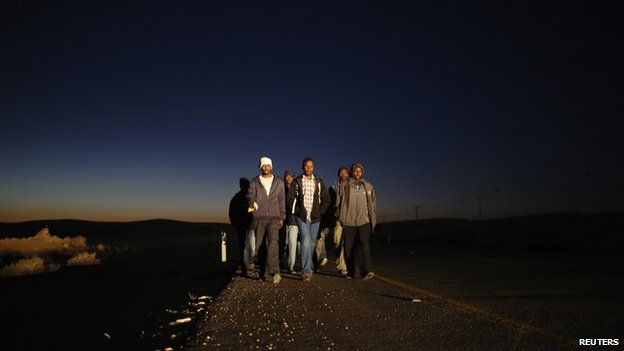 African migrants walk on a road after abandoning a detention facility in the southern Israeli desert (December 15, 2013)