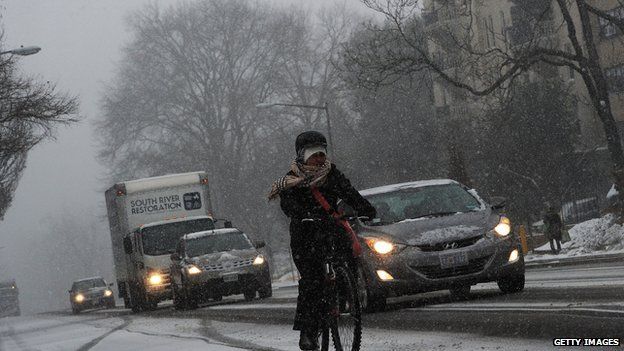 Commuters make their way under a snowfall on January 21, 2014 in Washington, DC