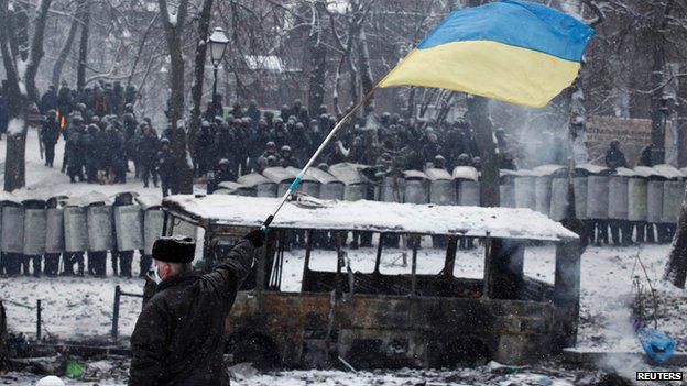 Man waves Ukrainian flag in front of riot police in Kiev on 22 January 2014