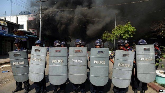 This file picture taken on March 22, 2013 shows policemen forming a line as they block access to part of the town where a house is burning in riot-hit Meiktila, central Myanmar