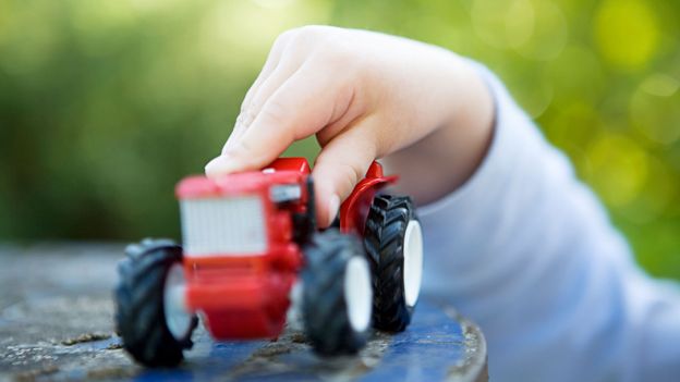 Child's hand holding toy tractor