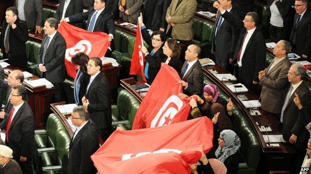 Members of the Tunisian National Constituent Assembly (NCA) wave flags to celebrate the adoption of a new constitution on 26 January 2014, in Tunis.