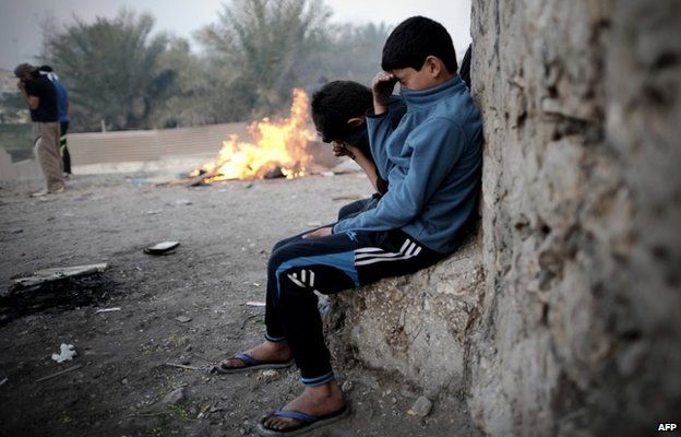 Boys cover their eyes and noses after tear gas is fired at protesters after the funeral of Fadel Abbas in Diraz (26 January 2014)