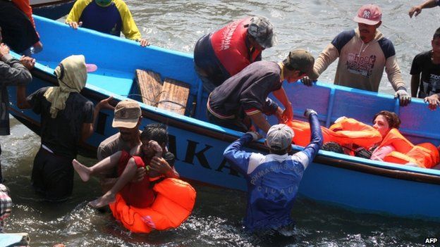 Rescuers assist survivors arriving on fishing boat at the wharf of Cidaun, West Java on 24 July 2013
