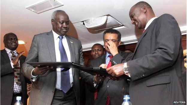 South Sudan's leader of the government's delegation Nhial Deng Nhial, left, exchanges a signed ceasefire agreement with the head of the rebel delegation General Taban Deng Gai, right