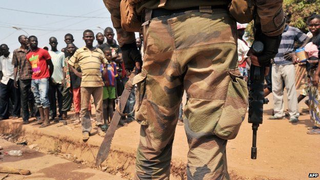 Local residents stand opposite a French soldier holding a machete confiscated from an anti-balaka combatant during a patrol in Bangui on 29 January 2014