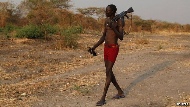 A rebel fighter with a weapon walks to a river to wash as he returns from a frontline in a rebel-controlled territory in Jonglei State, South Sudan (January 30, 2014)