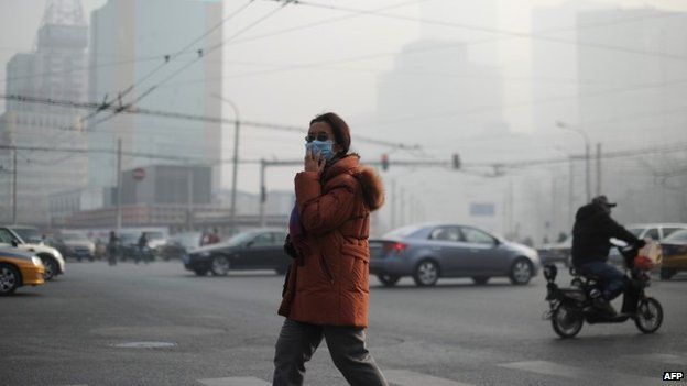 A woman wearing a face mask makes her way along a street in Beijing on January 16, 2014.