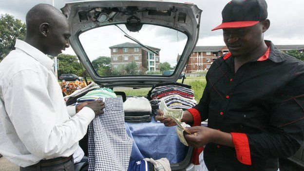 A clothes trader in Harare, Zimbabwe's capital, counting money by his car