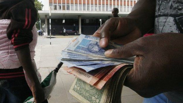 Someone holding South African rand and US dollars in Zimbabwe's capital, Harare