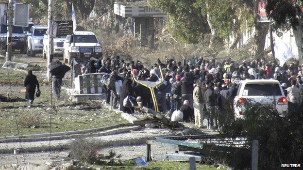Civilians gather before being evacuated with the help of Syrian Red Crescent and UN personnel from Homs on 9 February 2014