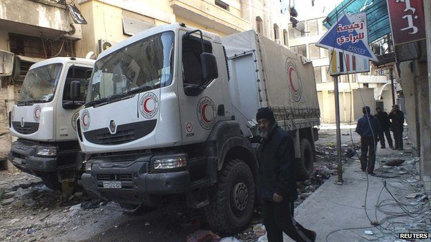 A man walks past damaged Syrian Red Crescent trucks in Homs on 9 February 2014
