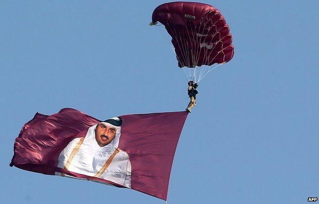 A paraglider pulls a flag showing Sheikh Tamim bin Hamad Al Thani on Qatar's National Day (December 2013)