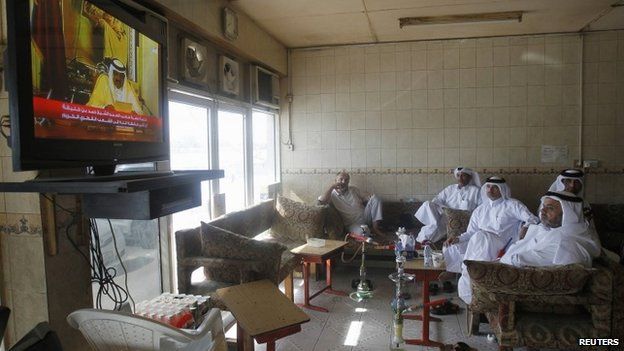 Qatari men watch a speech by Qatar's former emir in June 2013