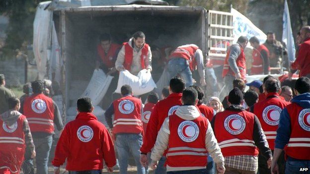Syrian Arab Red Crescent workers offload aid from a lorry as Syrians evacuated from rebel-controlled districts that were besieged by the army, arrive at a government-ruled area, in the central Syrian city of Homs, on Wednesday