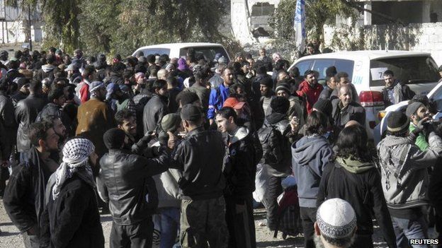 Civilians gathered near Syrian Arab Red Crescent and United Nations vehicles wait to be evacuated from a besieged area of Homs on Wednesday
