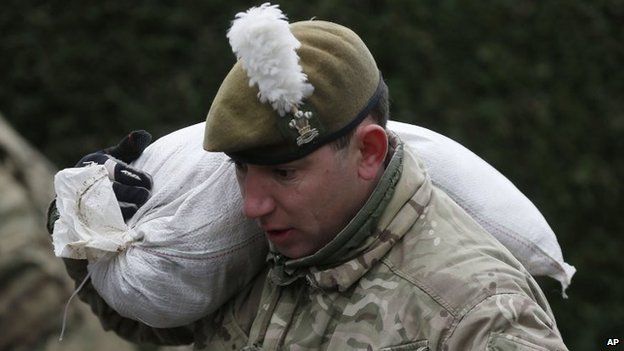A British Army soldier carries a sandbag over his soldier