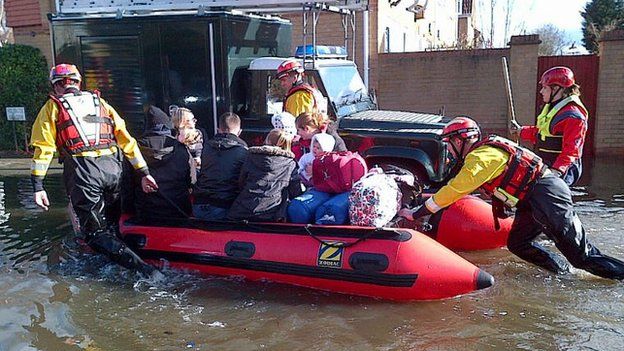 A specialist rescue team push a family through flood water on a boat