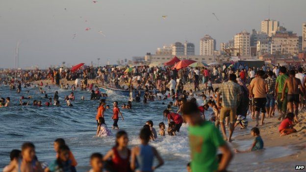 Palestinians are seen at the beach as the sun sets during a summer's day in Gaza City