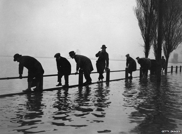 Men standing on fence in flood, Lea Bridge Road 1928