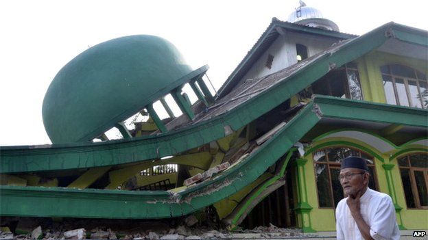 An elderly man walks past a collapsed mosque in Kranggan village after an earthquake in Banyumas, Central Java, on 25 January 2014