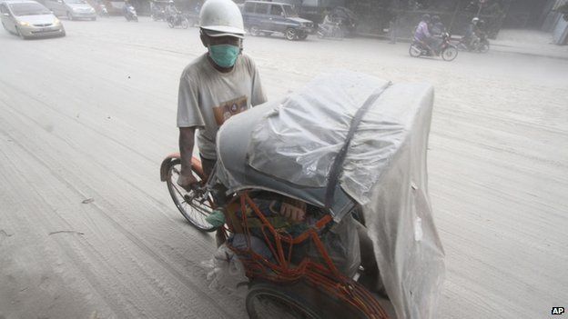 A pedicab makes its way on a street covered with volcanic ash from an eruption of Mount Kelud, in Solo, Indonesia, 14 February 2014