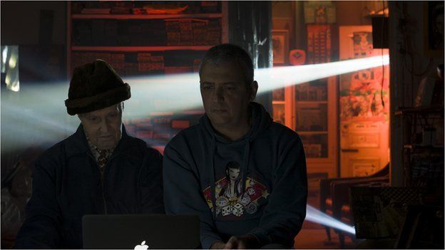 the artist and the photographer look at a computer screen in the photographers' studio