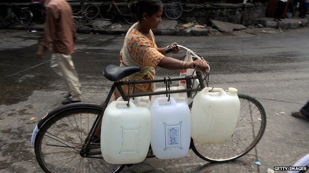 woman transporting water bottles on a bicycle, India