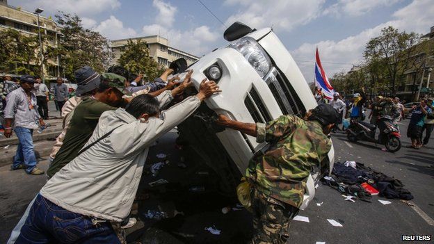 Anti-government protesters lift a police car after clashes with Thai riot police officers near Government House in Bangkok, 18 February 2014