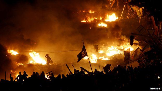Anti-government protesters stand behind burning barricades in Kiev's Independence Square on 19 February 2014.