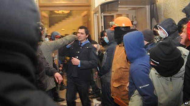 A policeman, centre, tries to stop Ukrainian protesters as they seize police headquarters in Lviv, western Ukraine, early on Wednesday
