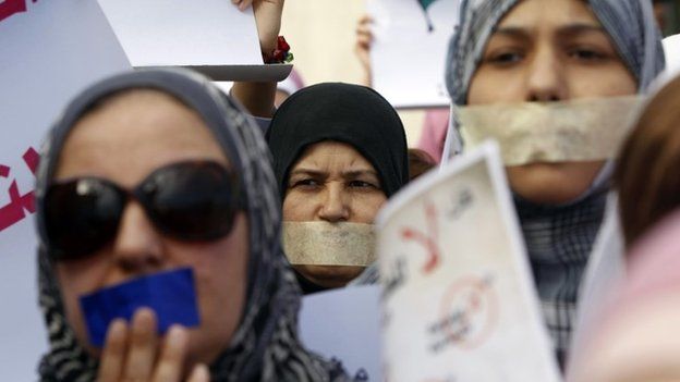 Libyan women with taped mouths take part in a silent march in support of the women who were raped during the conflict in Libya, in Tripoli -26 November 2011