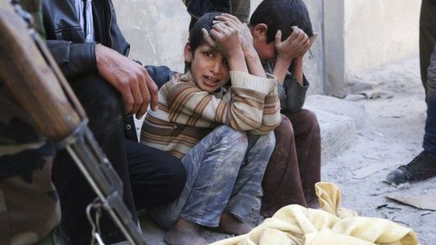 Children react next a body bag after what activists said was a barrel bomb attack in the al-Andhirat neighbourhood of Aleppo on 22 February.