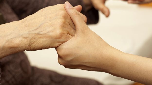 Old person holding hands with carer