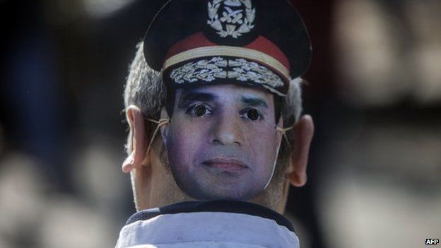 A supporter of Egypt's army chief Field Marshal Abdel Fattah al-Sisi, who is to run for the presidency in the upcoming elections, wears a mask bearing the image of the military commander