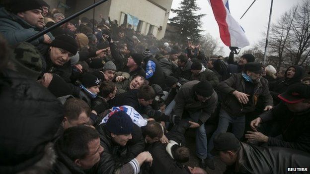 Ukrainian men help pull one another out of a stampede during clashes on Wednesday