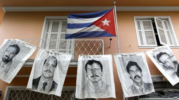 Плакаты с портретами пяти кубинцев, заключенных в тюрьму в Соединенных Штатах, показаны на этой фотографии из архива от 7 апреля 2010 года перед консульством Кубы в Сан-Пабло, Бразилия