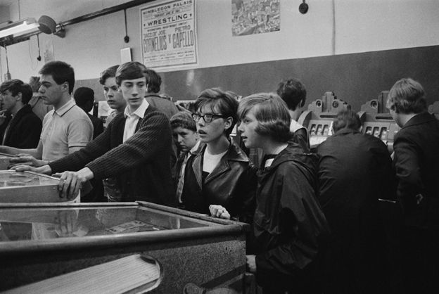 Teenagers playing pinball, 1964