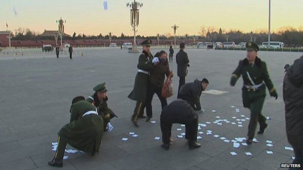 A video grab shows a protester being restrained, as paramilitary officers pick up leaflets during a protest in Tiananmen Square in Beijing, 5 March 2014