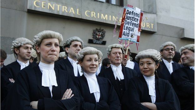 Barristers outside the Central Criminal Court with a placard reading: "Defend justice; defend legal aid."