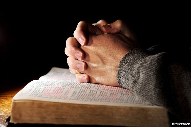Hands in prayer over Bible