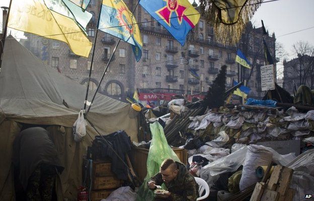 A member of a self-defence group eats breakfast next to a barricade in Kiev's Independence Square (7 March 2014)