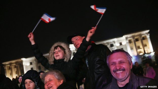People, including a woman waving Crimean flags, attend an outdoor performance of Russian Crimean folk music on 7 March 2014 in Simferopol, Ukraine