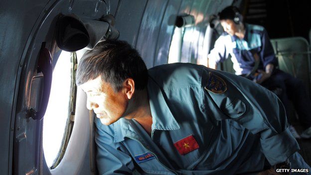 Military personnel scanning the sea aboard a Vietnamese Air Force aircraft taking part in a search mission for a missing Malaysia Airlines aircraft on 8 March 2014